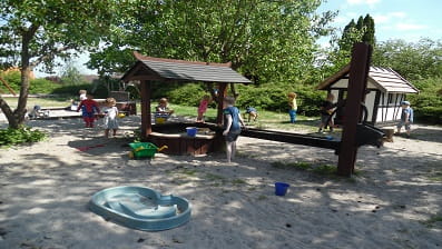 Børnene leger på legepladsen i solen