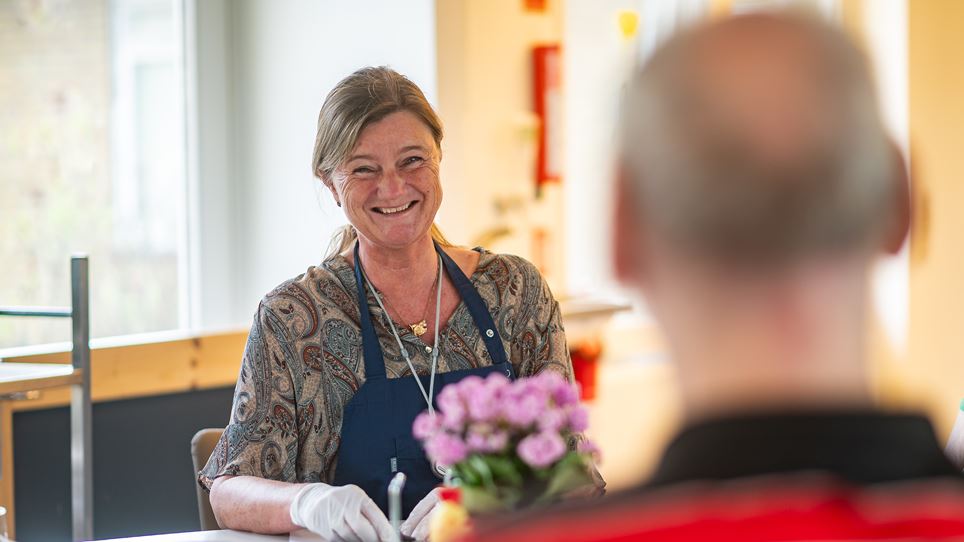 En medarbejder sidder og smiler til en borger.