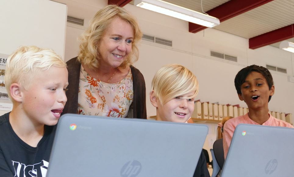 Susanne Crawley kigger på computer med børnene